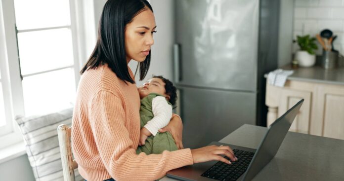 Mother, baby and laptop in kitchen for remote work.