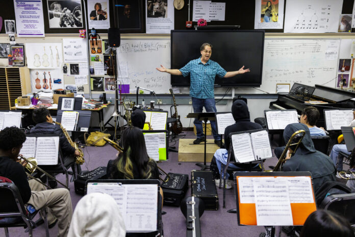 Man stands in front of students in band class.