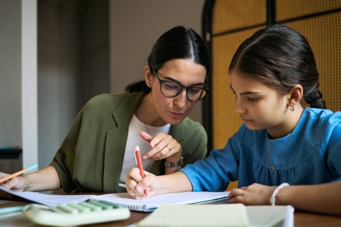 Woman helping girl with school work.